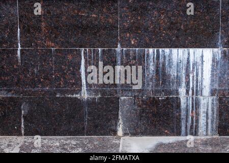 flat wall with rectangular natural tan brown granite tiles with white mineral drips. Stock Photo