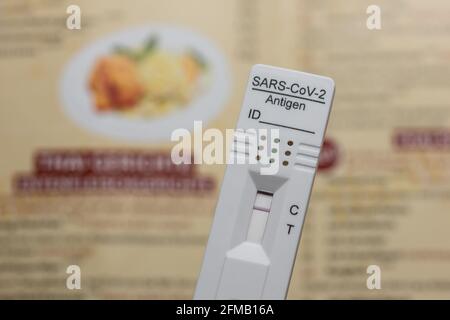 Testing Before Going To A Restaurant: Rapid Antigen Corona Test Showing A Negative Result In Front of A Menu, Berlin, Germany Stock Photo