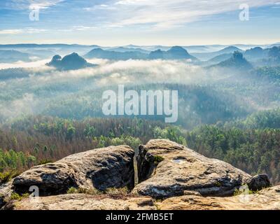 Germany, Saxony, Elbe Sandstone Mountains, Saxon Switzerland National Park, view over the Kleiner Zschand to Lorenzsteine and Hinteres Raubschloss or Winterstein with crevice in the morning light, fog in the valley Stock Photo