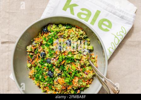 A gray bowl with colored broccoli salad and kitchen towel labeled 'kale' (cabbage). Stock Photo