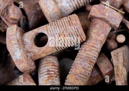 Old rusty bolts and nuts. Fasteners on the trash can. The iron bolts are rusty. Corrosion of metal on the screws. Stock Photo