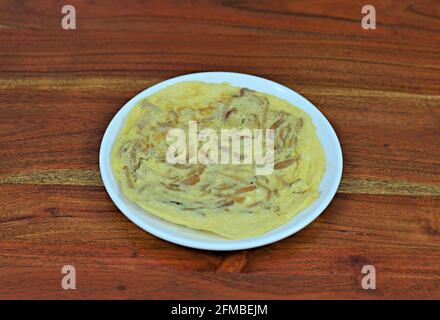 White plate of Spanish onion omelette on a wooden table Stock Photo