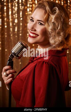 Young woman with Marilyn Monroe style blonde hair with microphone Stock Photo