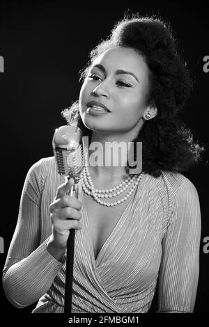 Dark skinned 1950s style singer with microphone Stock Photo