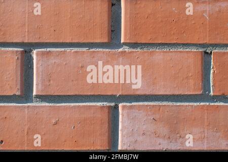 background, texture, pattern of smooth, geometrically adjusted neat red brick with traces of fresh, new plaster, view from the wall Stock Photo