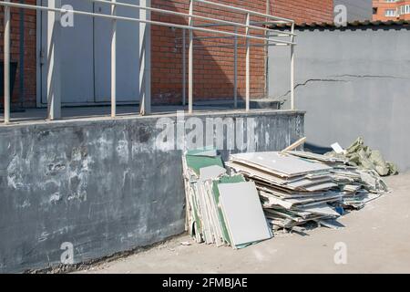 a pile of construction debris, broken drywall, lies near a brick building in a new area of residential buildings under construction Stock Photo