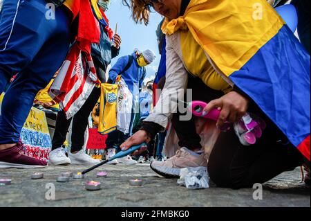A woman is seen lighting candles in memory of the ones who have died during the demonstrations in Colombia. Tens of thousands of Colombians have joined protests in the country's major cities against a proposed tax reform. More than 800 people are reported to have been injured during the clashes between the police and demonstrators. In The Netherlands, the Colombian community gathered at the Dam Square, in the center of Amsterdam to show their support with the people in Colombia, and to make it possible for people to know what is happening in their country. From the Dam, they marched to protest Stock Photo