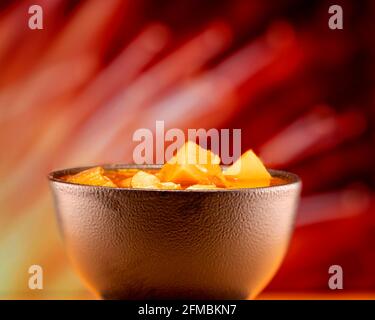 Vegetable stew in a ceramic bowl against a red and yellow background Stock Photo