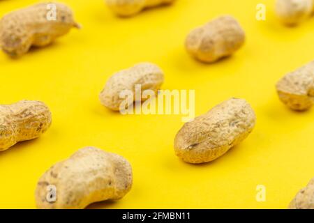 Pattern of peanuts with shell. Fashionable sunny pattern of peanuts with shell on yellow background. Colorful pattern. Stock Photo