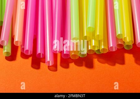 Colored tubules for juice and cocktails on orange background. Cocktail parties. Space for text. Stock Photo