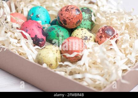 colored quail eggs in a basket lie Stock Photo