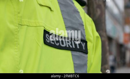 Close up of security guard in light green uniform standing by on the street day time Stock Photo