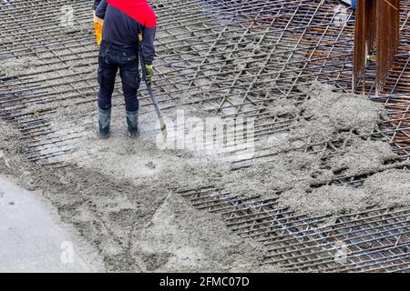 Construction worker using concrete vibrator for compacting concrete to eliminate voids and increases concrete density and strength. Stock Photo