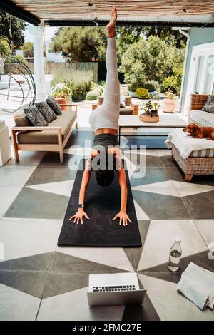 Mixed race female teen stretching legs practicing yoga outside home Stock Photo