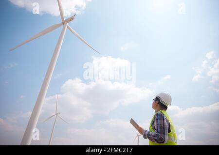 Successful engineer windmills using tablet with wind turbine in background Stock Photo