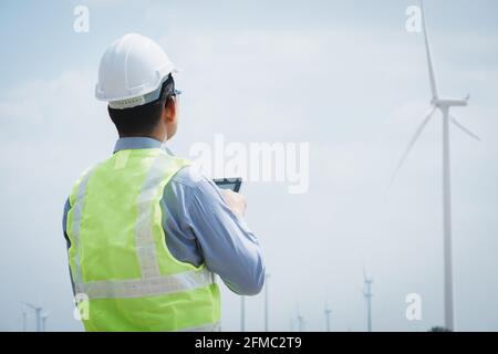 Engineer windmills using tablet with wind turbine in background Stock Photo