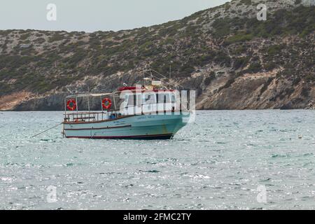 Island, Greece - 28 September 2020: Boat from tourists moored at the bay. Hills in the background. Stock Photo