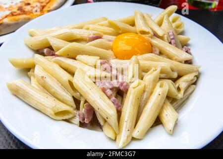 Pasta penne ala carbonara with egg yolk and ham in Paris, France. Stock Photo