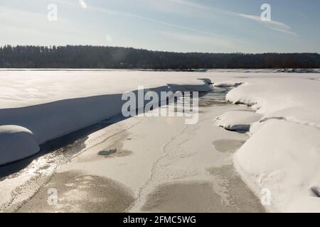 thawed patch with water on river among snow. Stock Photo