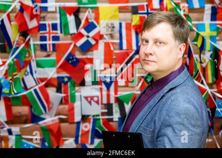 Adult male businessman with pen and folder in hands on background of flag. Stock Photo