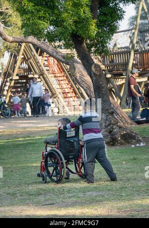 Tel Aviv, Israel - March 31st, 2021: A boy pushing his disabled brother's wheelchair in a Tel Aviv, Israel, Park. Stock Photo