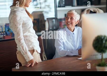 A female boss talking to her young female colleague in a pleasant atmosphere at the workplace. Business, office, job Stock Photo
