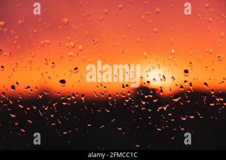 Drops of rain water on the window against the evening sky. Raindrops on the glass, sunset, weather related image Stock Photo
