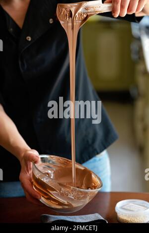 The pastry chef tempered hot milk chocolate. Cooking desserts. Soft selective focus. Stock Photo