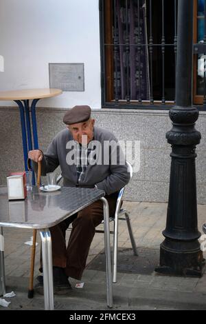 A grumpy old man sits at a table outside Bar La Puntilla, Guadalcanal, Andalucia, Spain Stock Photo