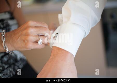 Man groom tying cufflinks on shirt sleeves getting dressed with closeup of hands no face. High quality photo Stock Photo