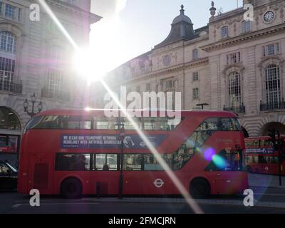 London, Greater London, England - May 04 2021: London Bus in Piccadilly Circus as the low evening light cascades over the buildings. Stock Photo