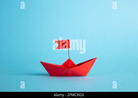 Leadership concept. Red leader paper ship leading among others on blue background. Stock Photo