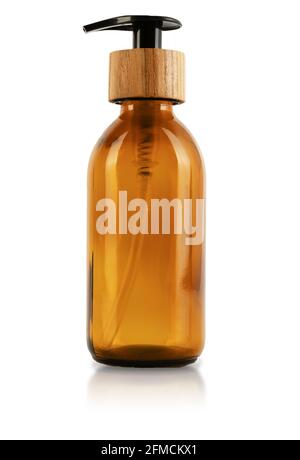 Brown glass bottle with dispenser and wooden stopper cap. Isolated on white background. Eco container for cosmetics. A container with a straw inside and a button for a pump for gel, lotion or shampoo. Stock Photo