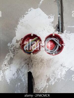 Electrical wires with cables at home repair. New electrical outlets. Socket on concrete wall Stock Photo