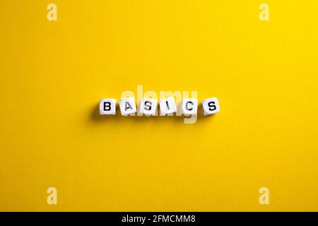 Basics word written on blocks on yellow background with flat lay view. Back to basics or simplifying business concept. Stock Photo