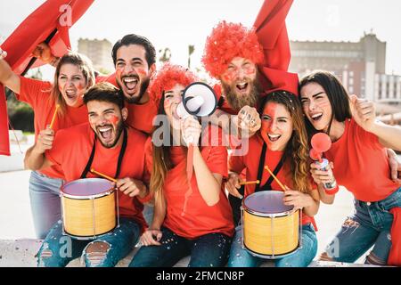 Football fans watching soccer match event at stadium - Young people having fun supporting favorite club - Sport entertainment concept Stock Photo