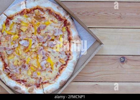 Pizza in a cardboard box on wooden background. Space for text. View from above. Pizza delivery. Pizza menu. Italian Pizza. Pizza Tonda Romana Stock Photo