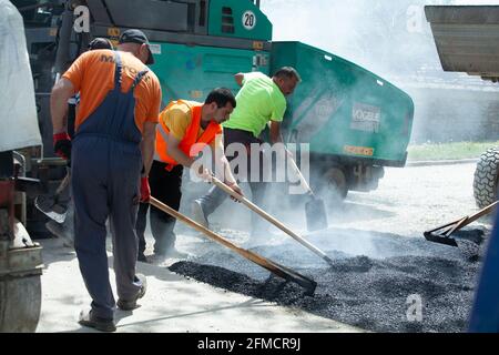 Mihaltsi, Bulgaria - May 7 2021: Workers leveling asphalt on a road with paving lutes and shovels Stock Photo