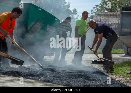 Mihaltsi, Bulgaria - May 7 2021: Workers leveling asphalt on a road with paving lutes and shovels Stock Photo