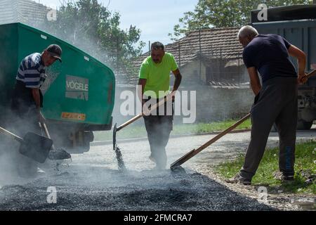 Mihaltsi, Bulgaria - May 7 2021: Workers leveling asphalt on a road with paving lutes and shovels Stock Photo