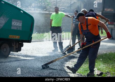 Mihaltsi, Bulgaria - May 7 2021: Workers leveling asphalt on a road with paving lutes and shovels Stock Photo