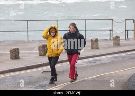 Cornwall, UK. 08th May, 2021. People were out walking despite the extremely strong winds in Porthleven, Cornwall. The Temperature was 12C, the forecast is for rain & strong winds over the next few days. Credit: Keith Larby/Alamy Live News Stock Photo