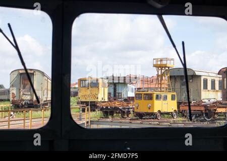 Old trains spotted behind an electric locomotive window in a vintage Italian train at the Piedmontese Railway Museum, Italy Stock Photo