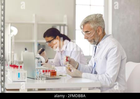 Old and young scientist working at science laboratory conducting experiment Stock Photo