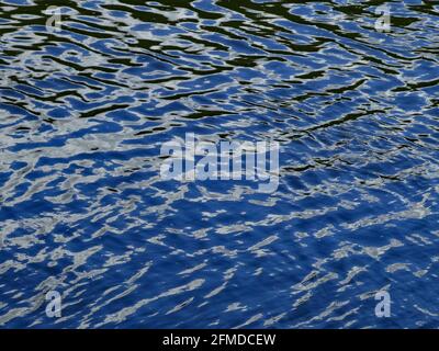 The surface of a river on a bright sunny day. The water reflects the blue sky. Blue water meant as background Stock Photo