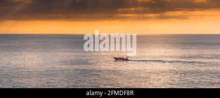 A panoramic image of the Newquay RNLI Atlantic 85 class inshore lifeboat Gladys Mildred speeding to Fistral Bay on an emergency call out in Cornwall. Stock Photo