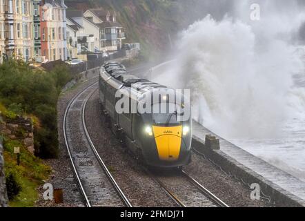 A Great western Railways Hitatchi Class 800 train passes along the refurbished Dawlish seawall, during stormy weather. GWR. Stock Photo