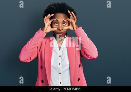 African american woman with afro hair wearing business jacket trying to open eyes with fingers, sleepy and tired for morning fatigue Stock Photo