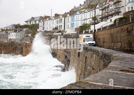 Porthleven,Cornwall,8th May 2021,A wave crashes over the harbour wall narrowly missing a delivery van in Porthleven, Cornwall. The Temperature was 12C and the forecast is for rain & strong winds over the next few days.Credit: Keith Larby/Alamy Live News Stock Photo