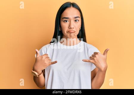 Young asian woman doing shaka sign with hands depressed and worry for distress, crying angry and afraid. sad expression. Stock Photo